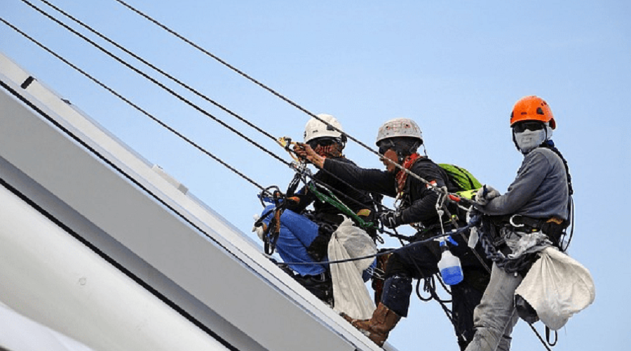Three workers doing safety training on a roof.