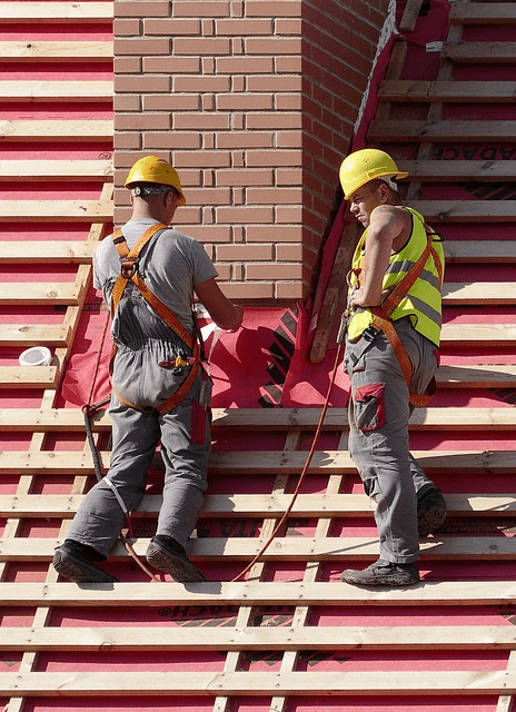 Two workers using fall protection gear while servicing a chimney.