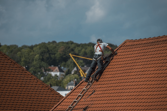 Worker in a steep roof on a ladder.