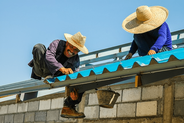 Two workers installing a metal roof.