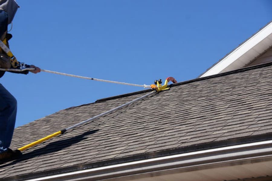Roofer using a Ridge Pro Steep Assist anchor for fall protection.