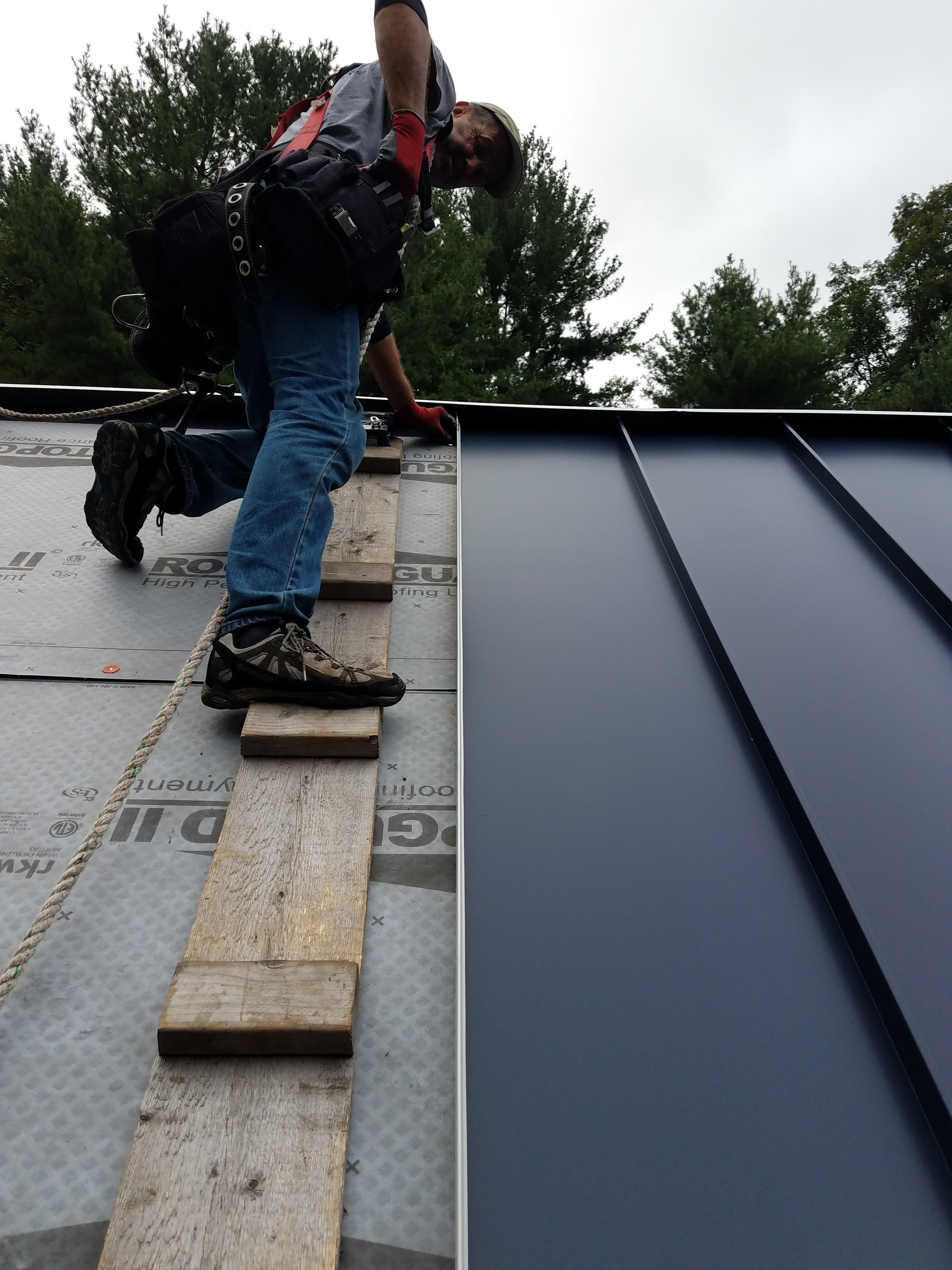 Worker installing standing seam roof panels. 