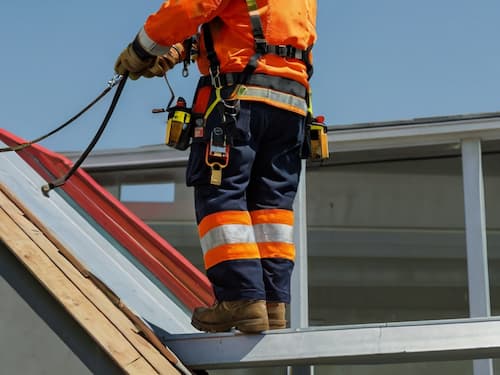 Worker using fall protection lanyards on a roof.