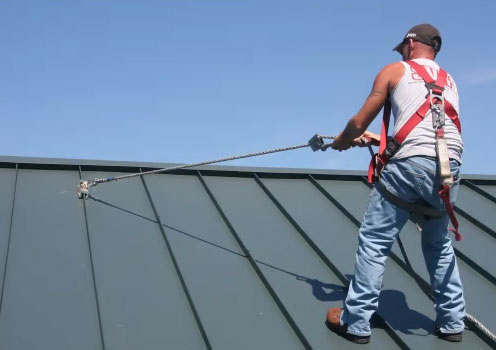 Worker using a SSRA1 anchor attached to a standing seam metal roof.