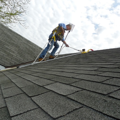 Worker using a RidgePro for fall protection on a shingle roof.