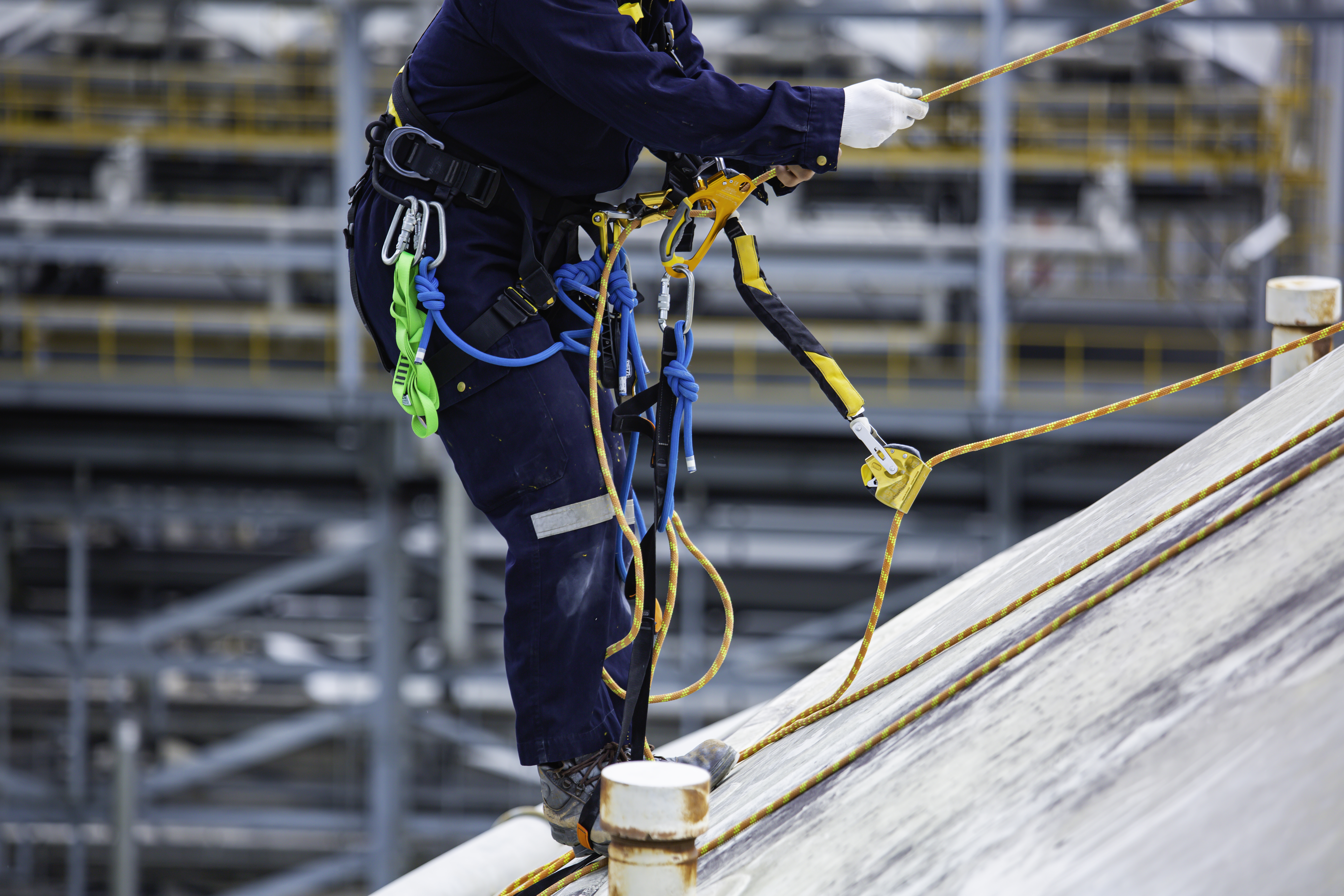 Roofer on steep roof using fall protecion equipment.