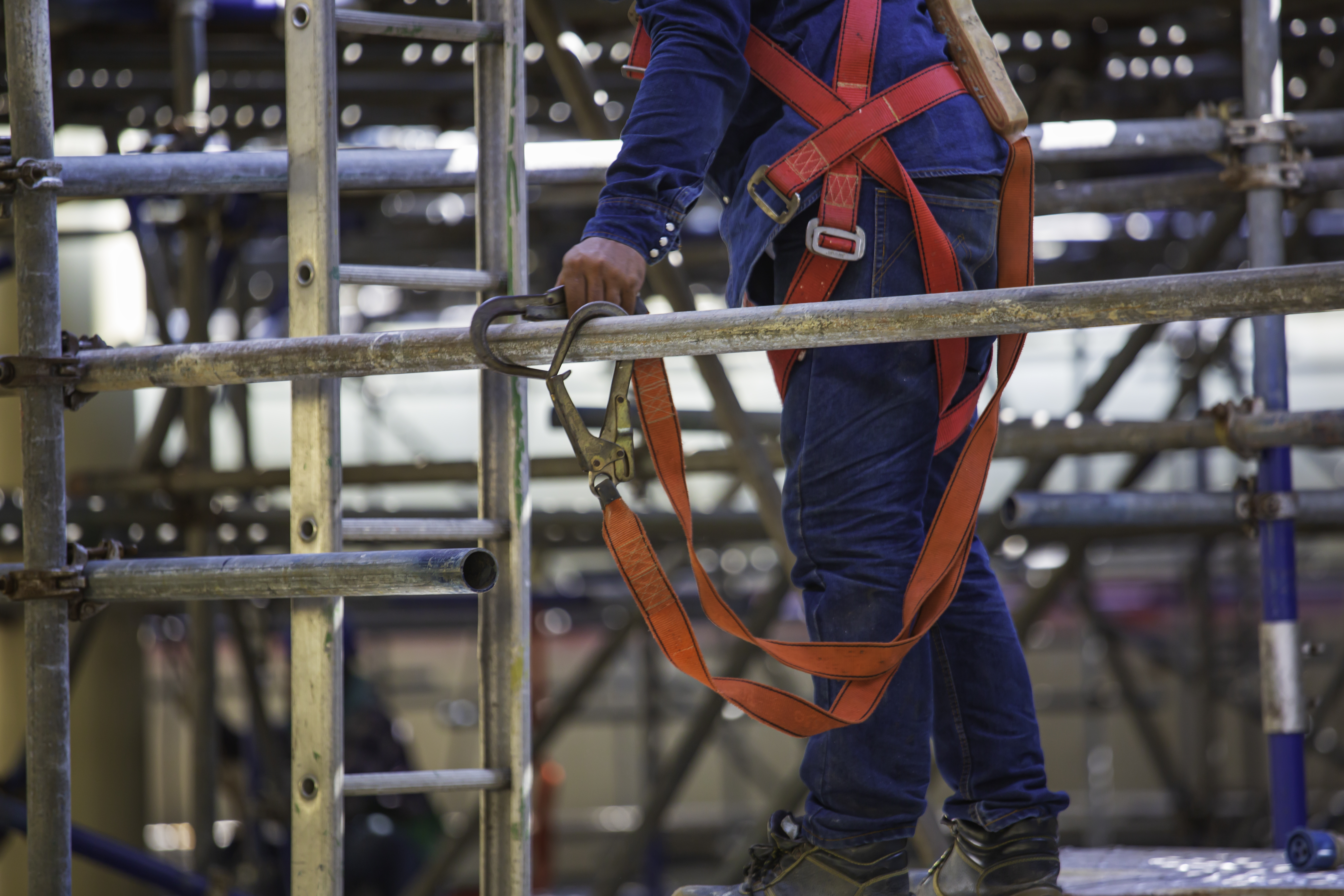 Worker using lanyards with carabiners to stay anchored for fall protection.