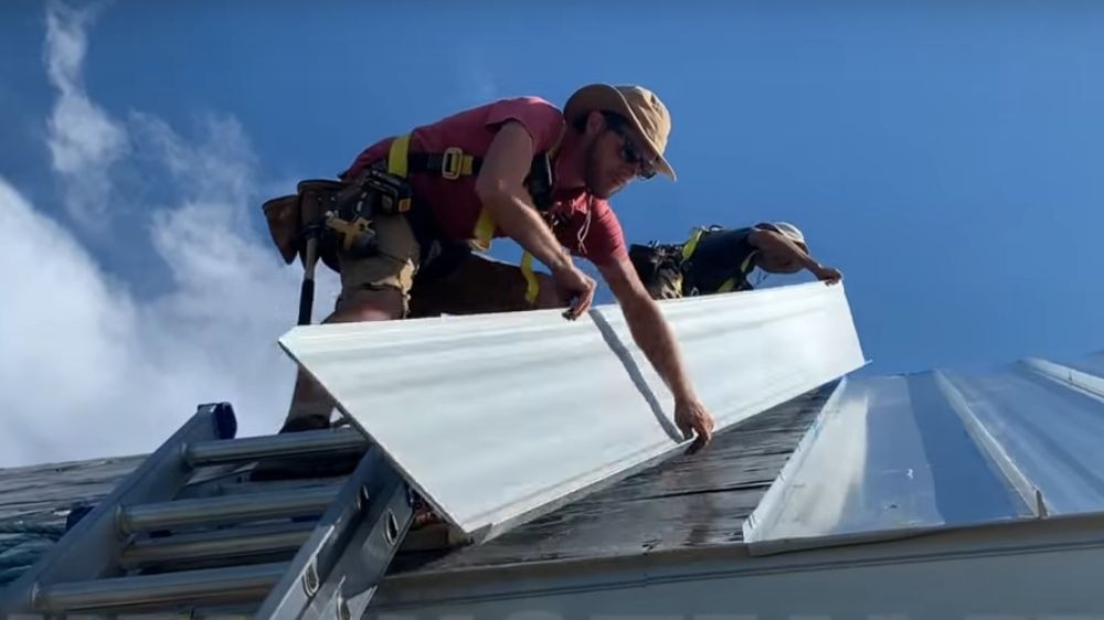 Roof workers installing standing seam metal roof panels.