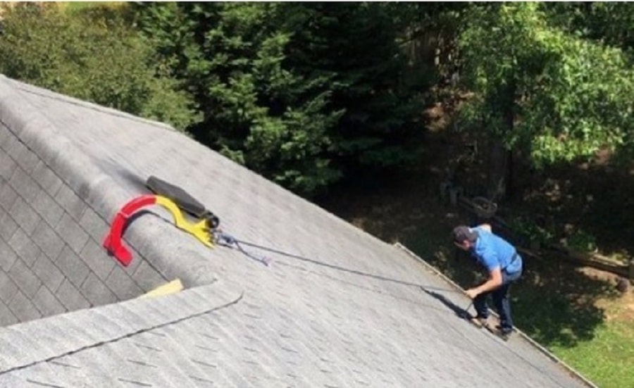 Worker anchored to the roof with a RidgePro hook over the peak.
