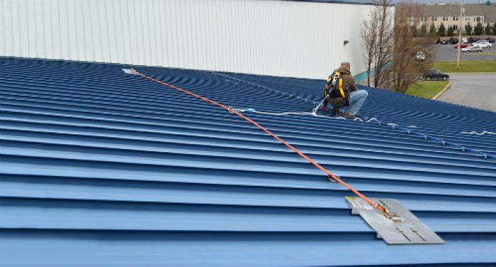 Worker using a SSRA HLL kit to stay anchored to a standing seam metal roof.